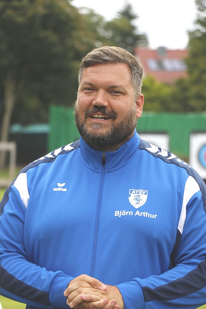 Björn Arthur Zuev, Jugendwart Bogen und Landesfachwart, in der blauen Vereinsjacke des ATSV Stockelsdorf auf dem Sportgelände.